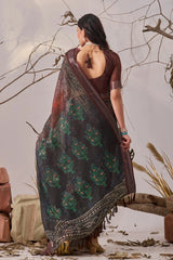 Woman wearing a dark saree with floral patterns in a natural setting