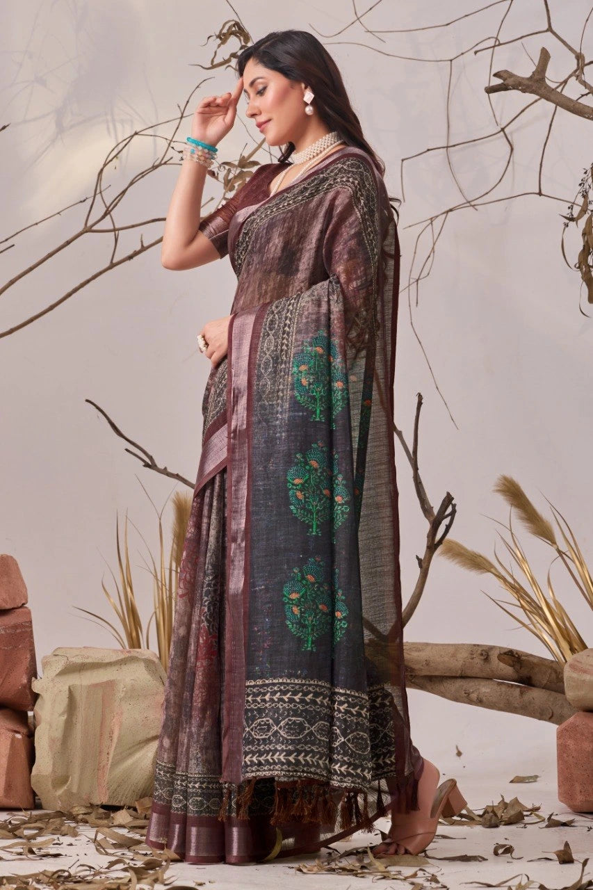 Woman in a traditional saree standing among dried plants and branches.