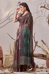 Woman in a traditional saree standing among dried plants and branches.
