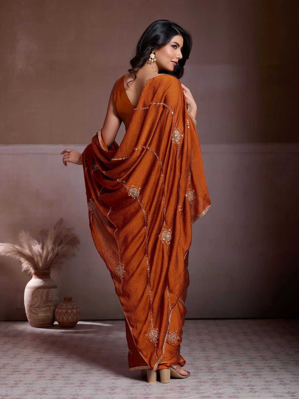 Woman wearing an orange saree with a plain background