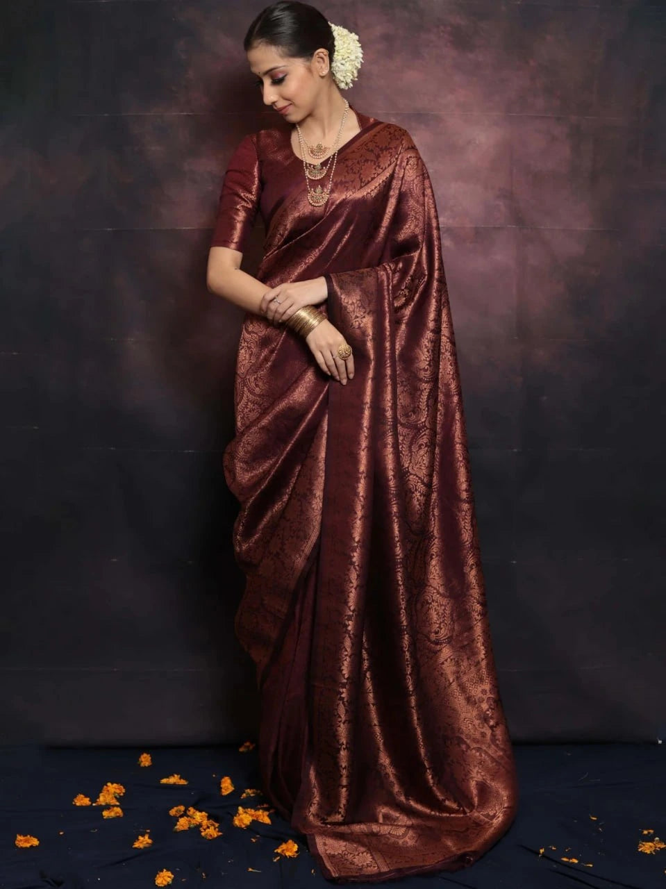 Woman wearing a maroon saree with a dark background