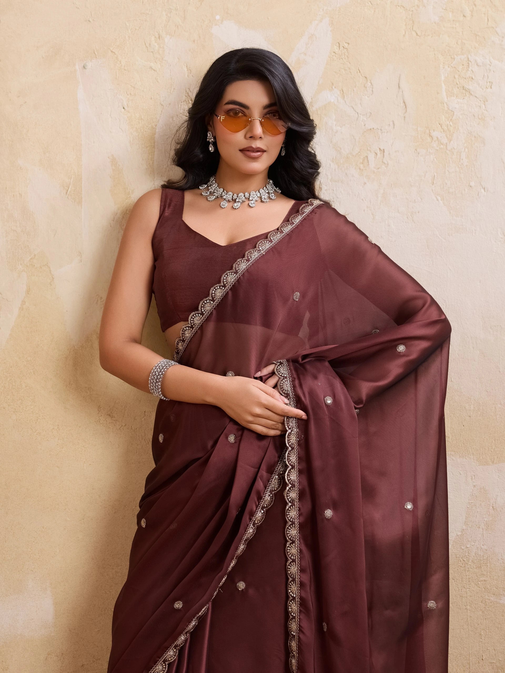Woman wearing a maroon saree with a textured beige background