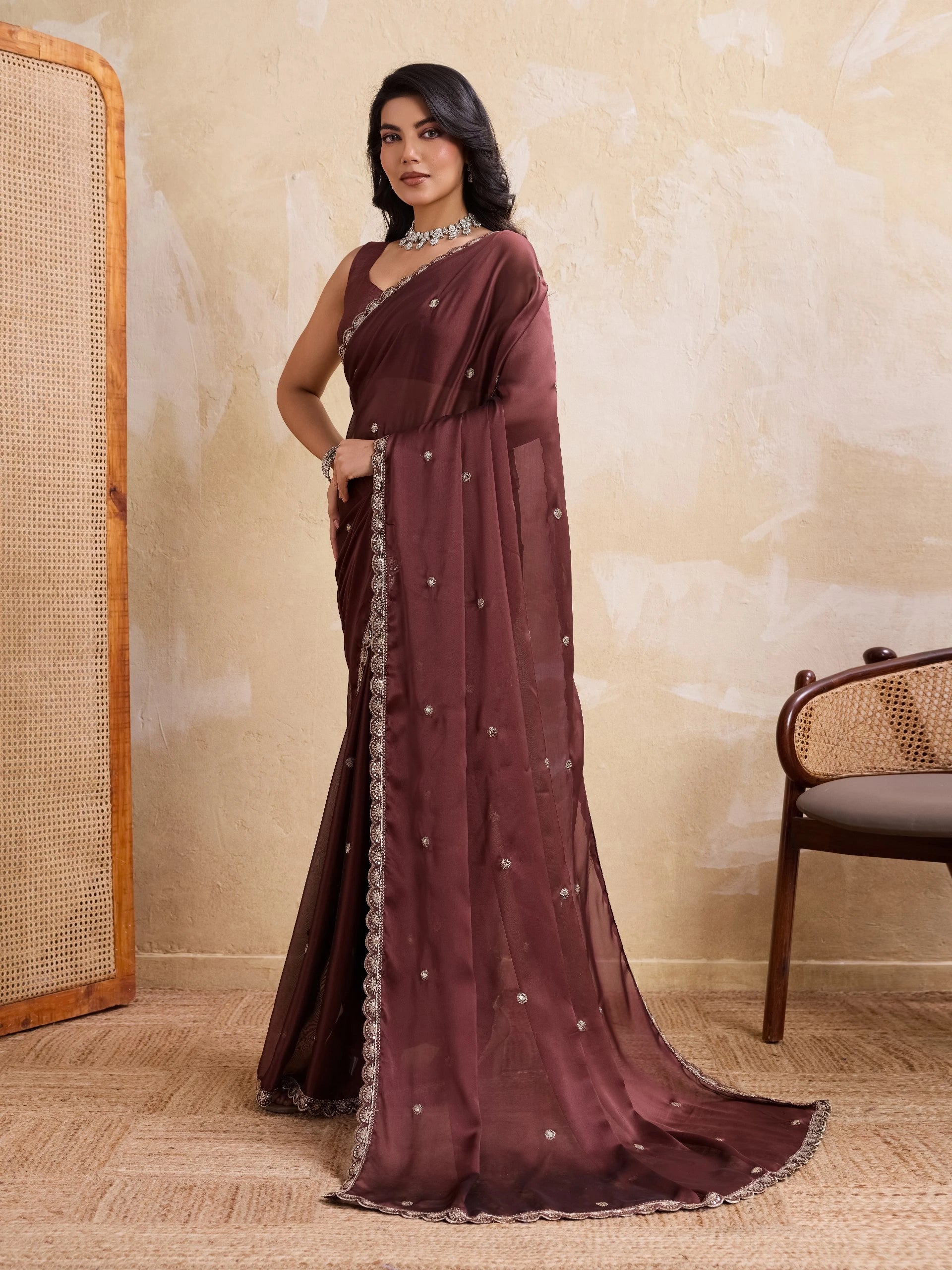 Woman wearing a maroon saree with a white border in an indoor setting.