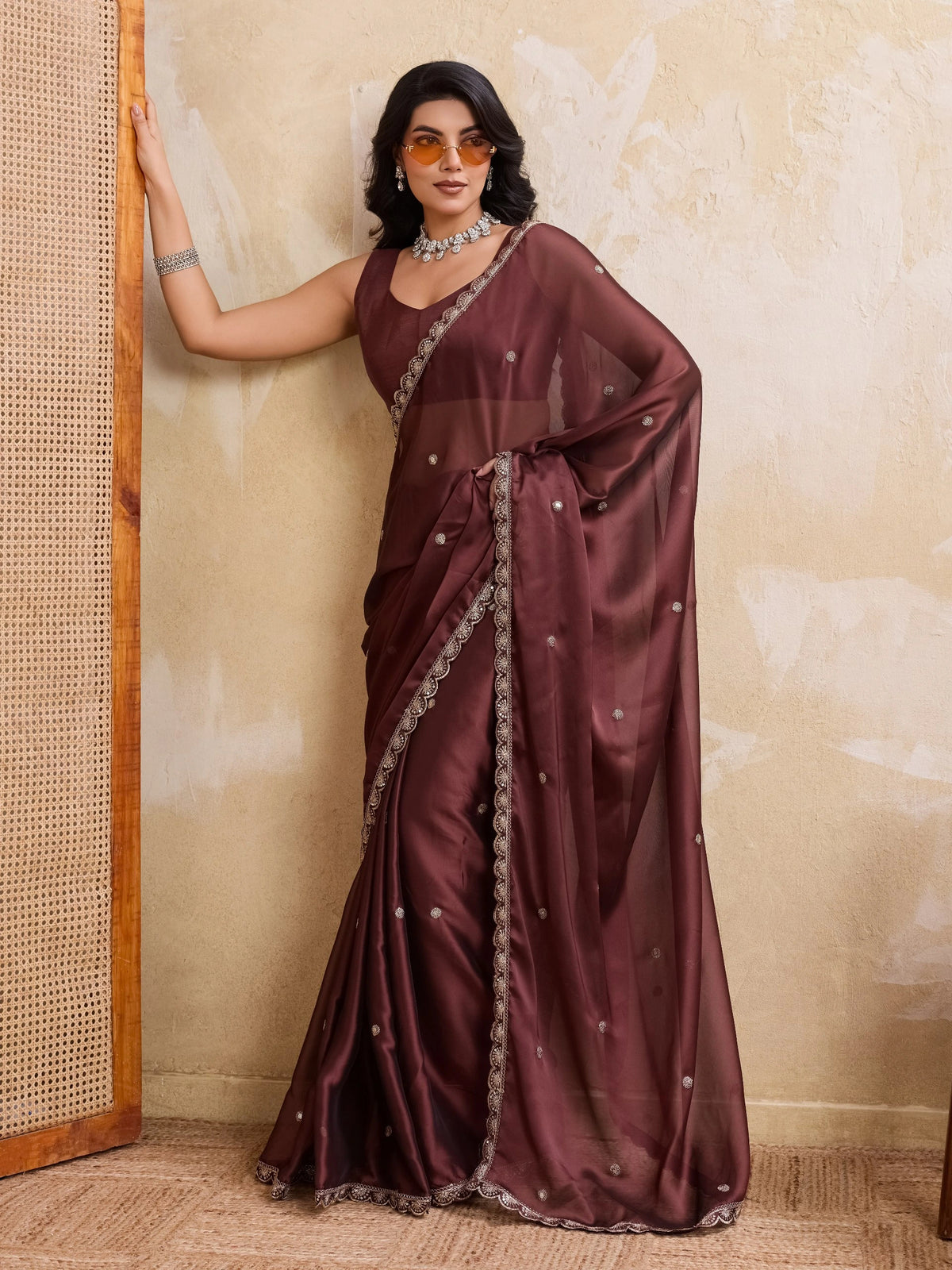 Woman wearing a maroon saree with a textured wall background