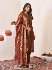Woman wearing a brown traditional outfit with a patterned background