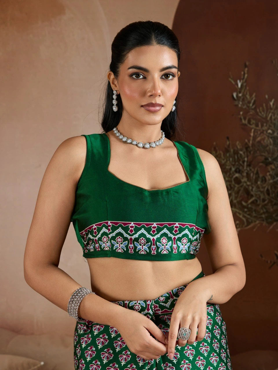 Woman wearing a green embroidered blouse with a patterned skirt against a brown background