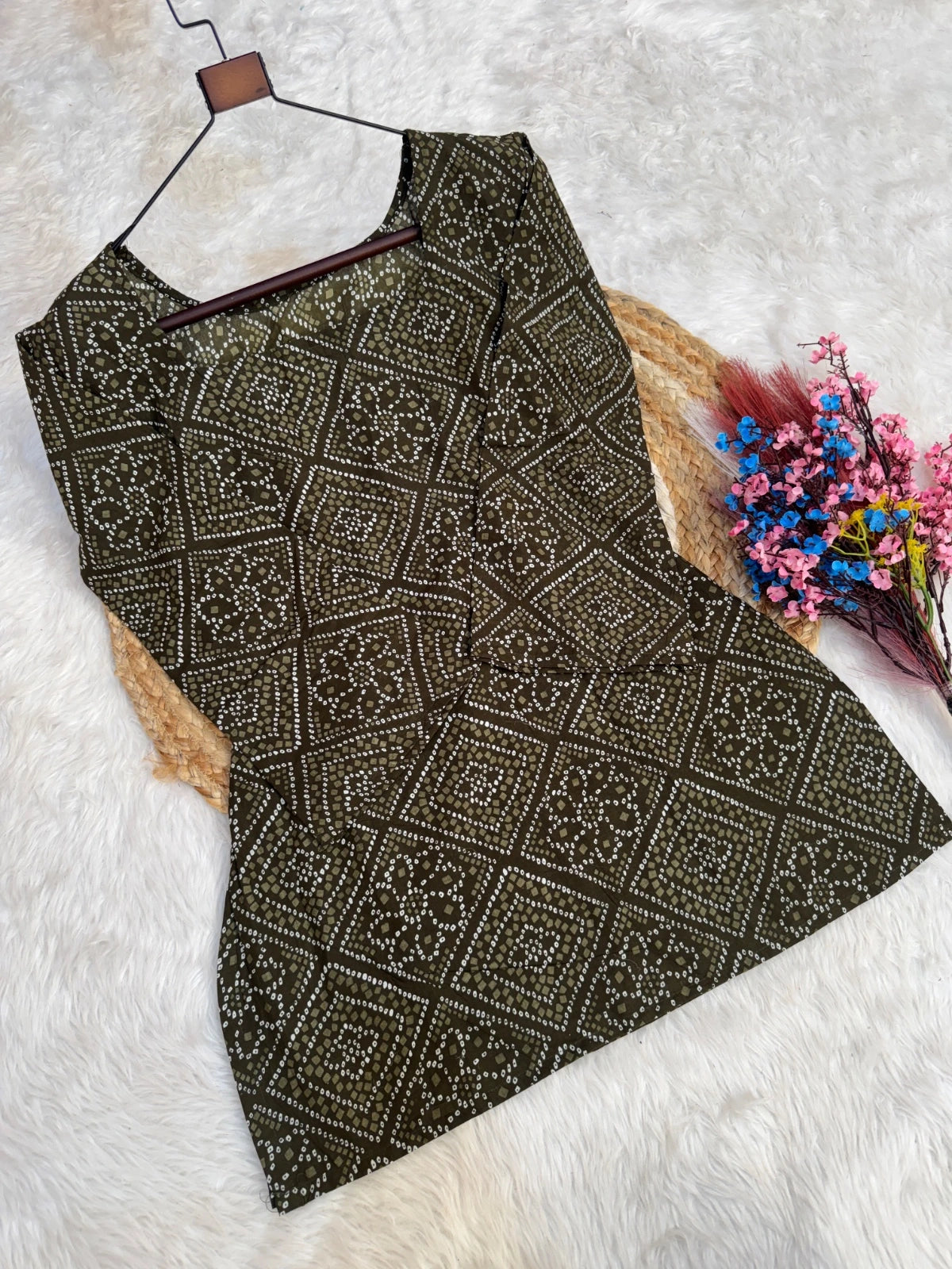 Black patterned dress on a hanger with flowers on a white background