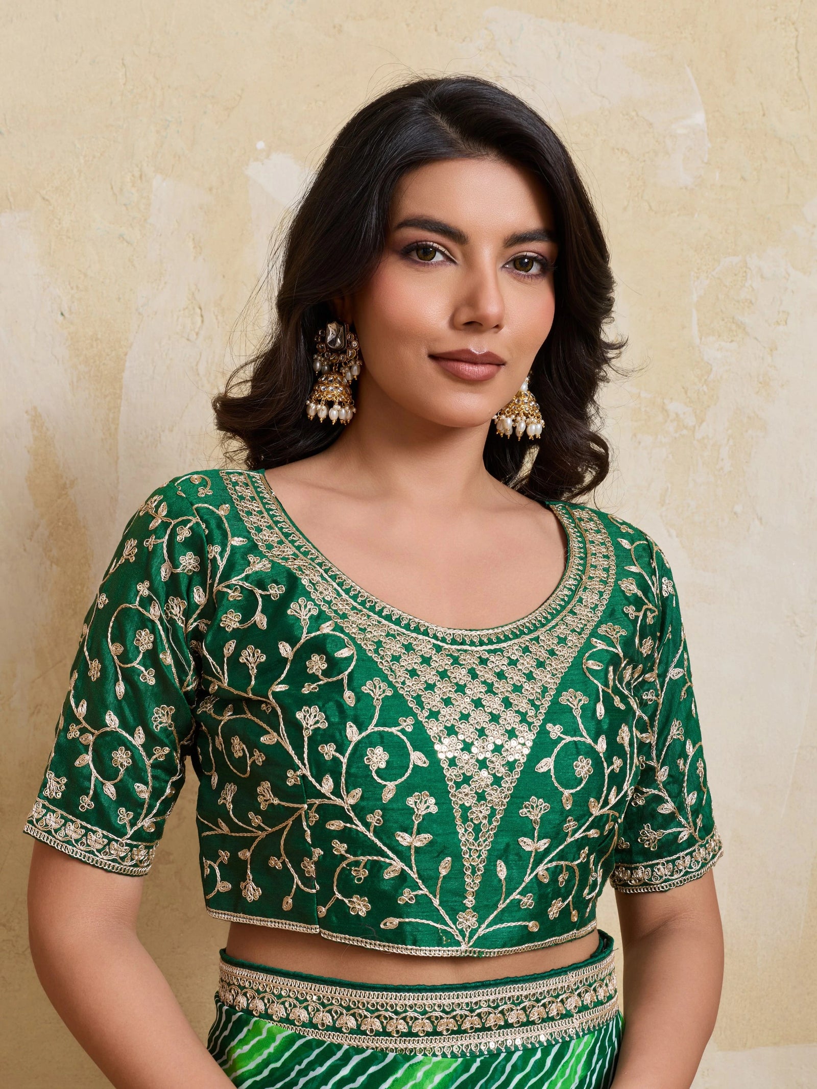 Woman wearing a green embroidered blouse against a beige background