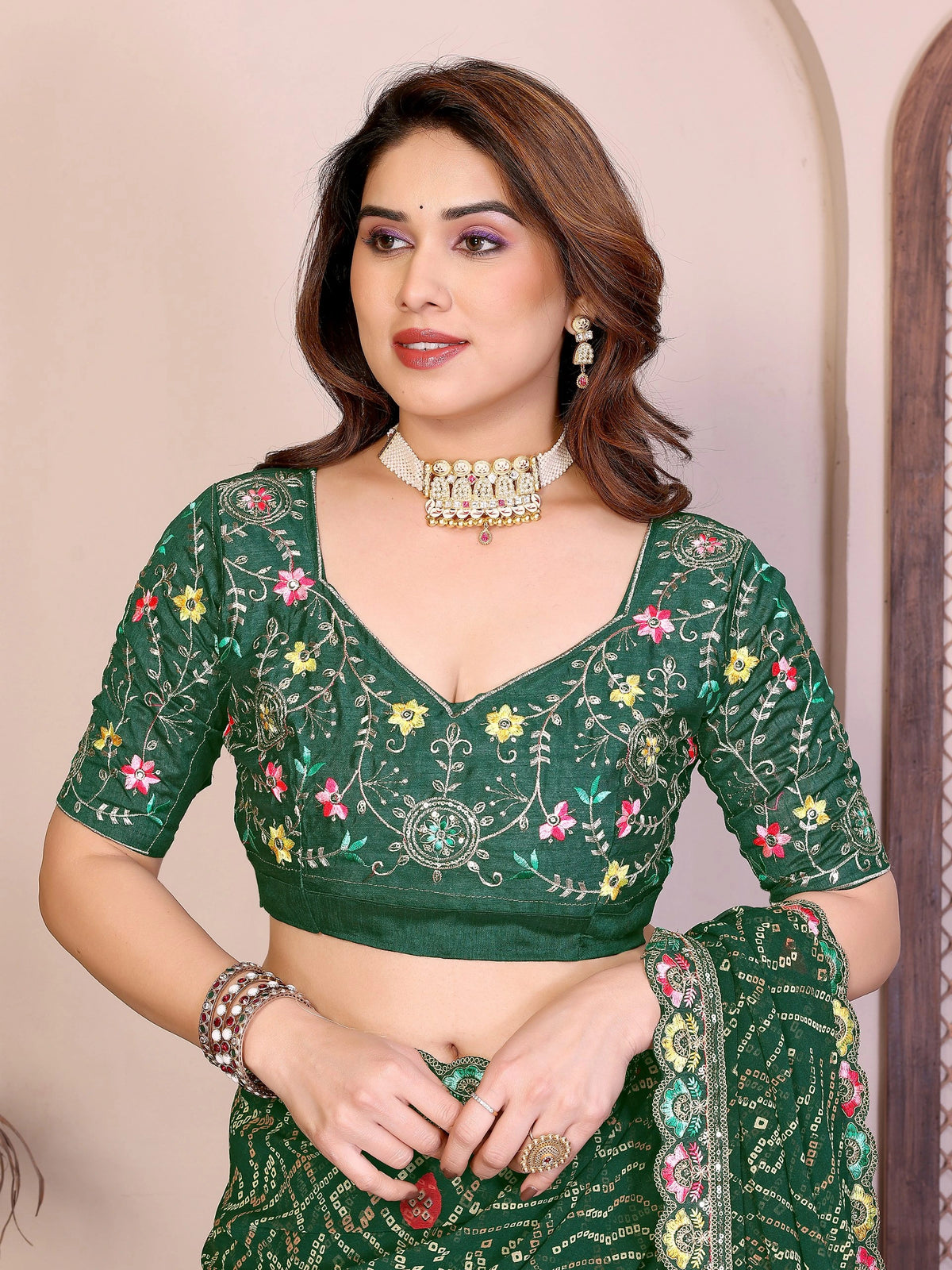 Woman wearing a green embroidered traditional outfit with a neutral background