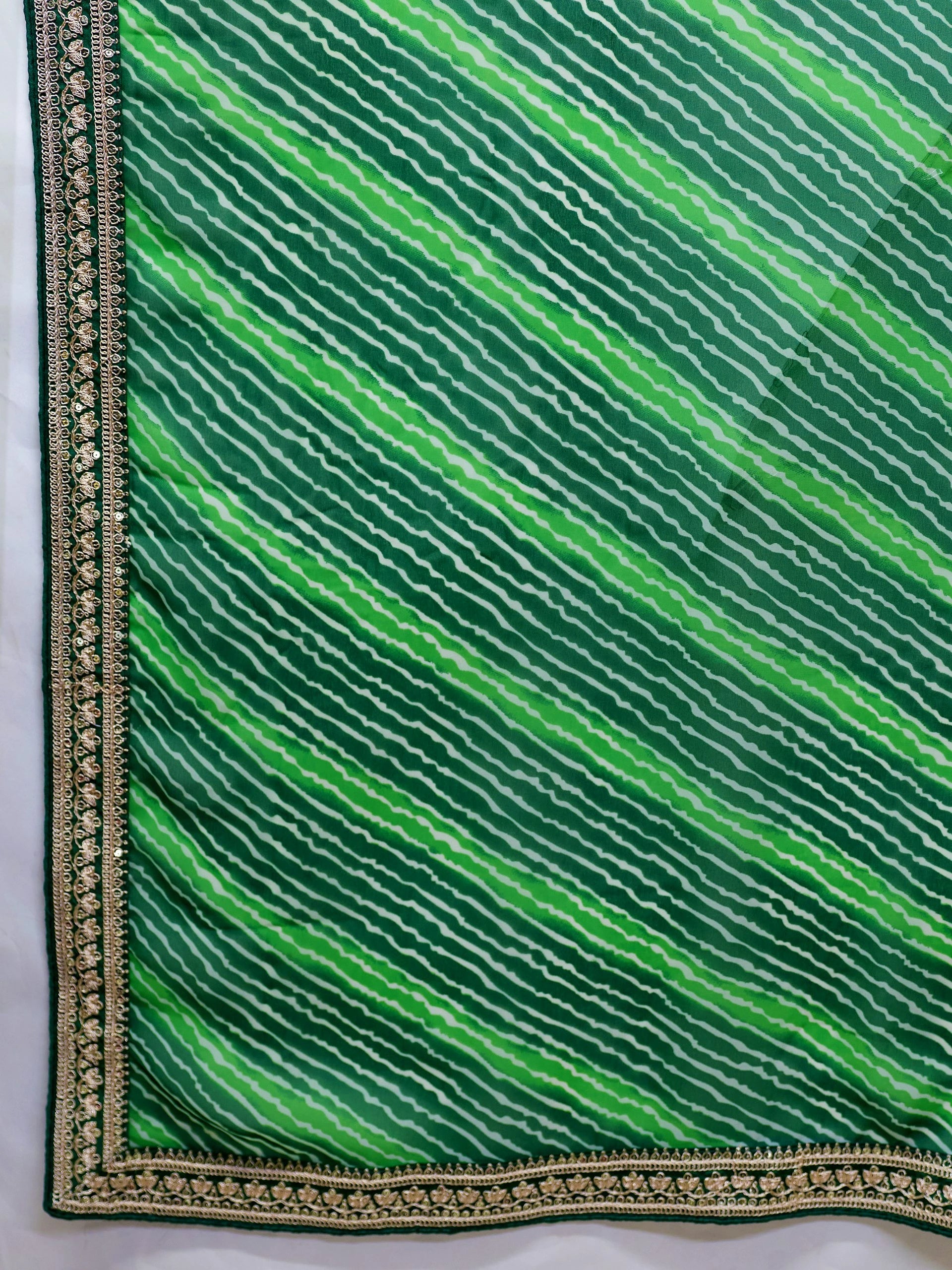 Green fabric with wavy pattern and gold border on a white background