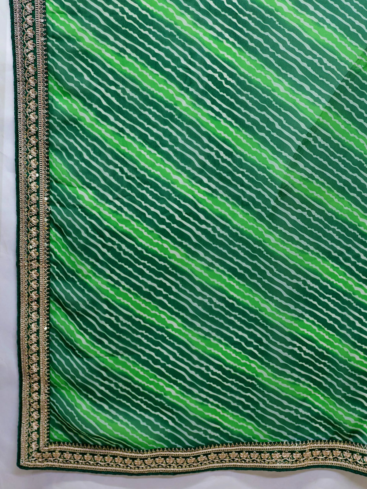 Green fabric with wavy pattern and gold border on a white background