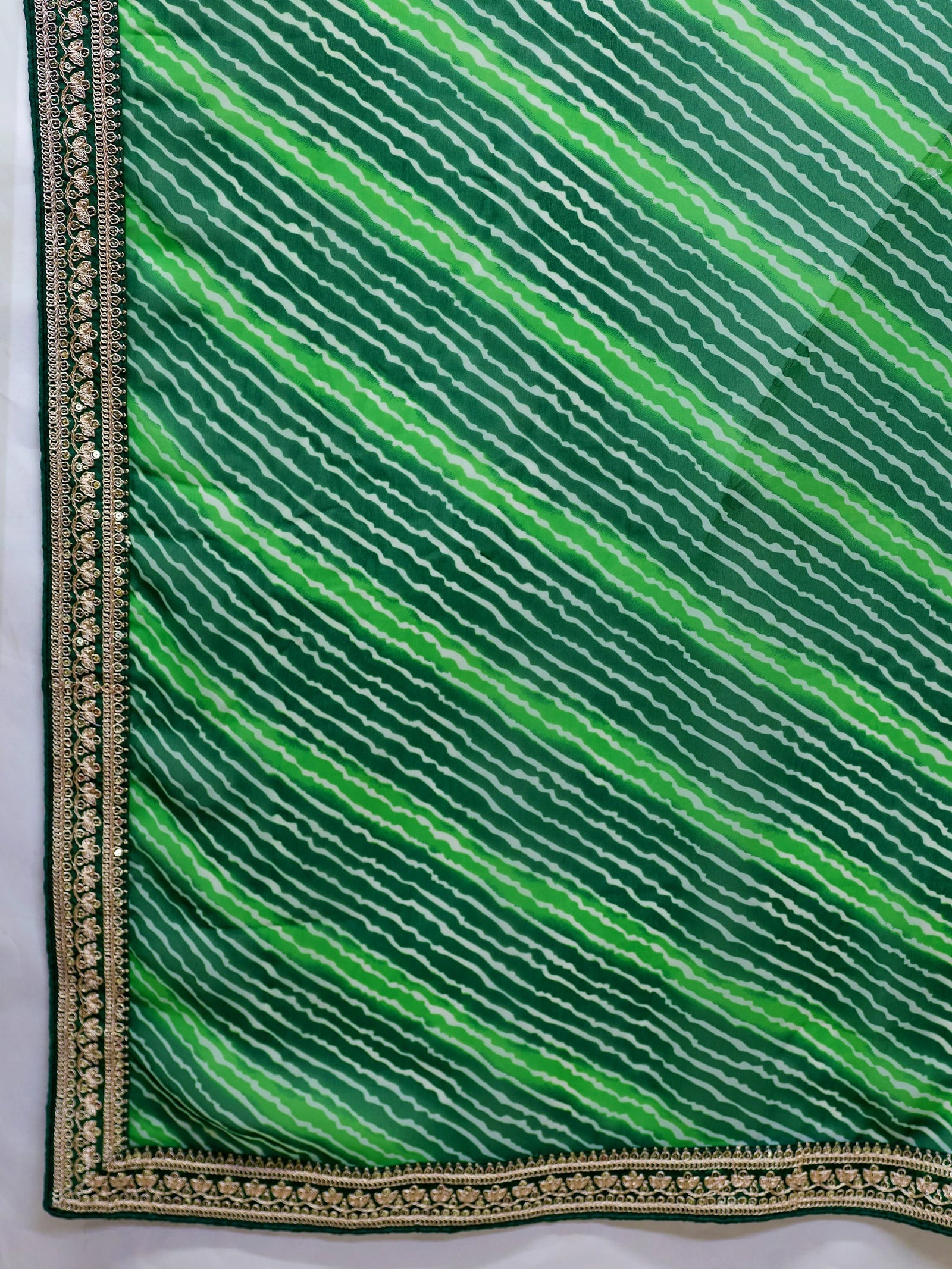 Green fabric with wavy pattern and gold border on a white background