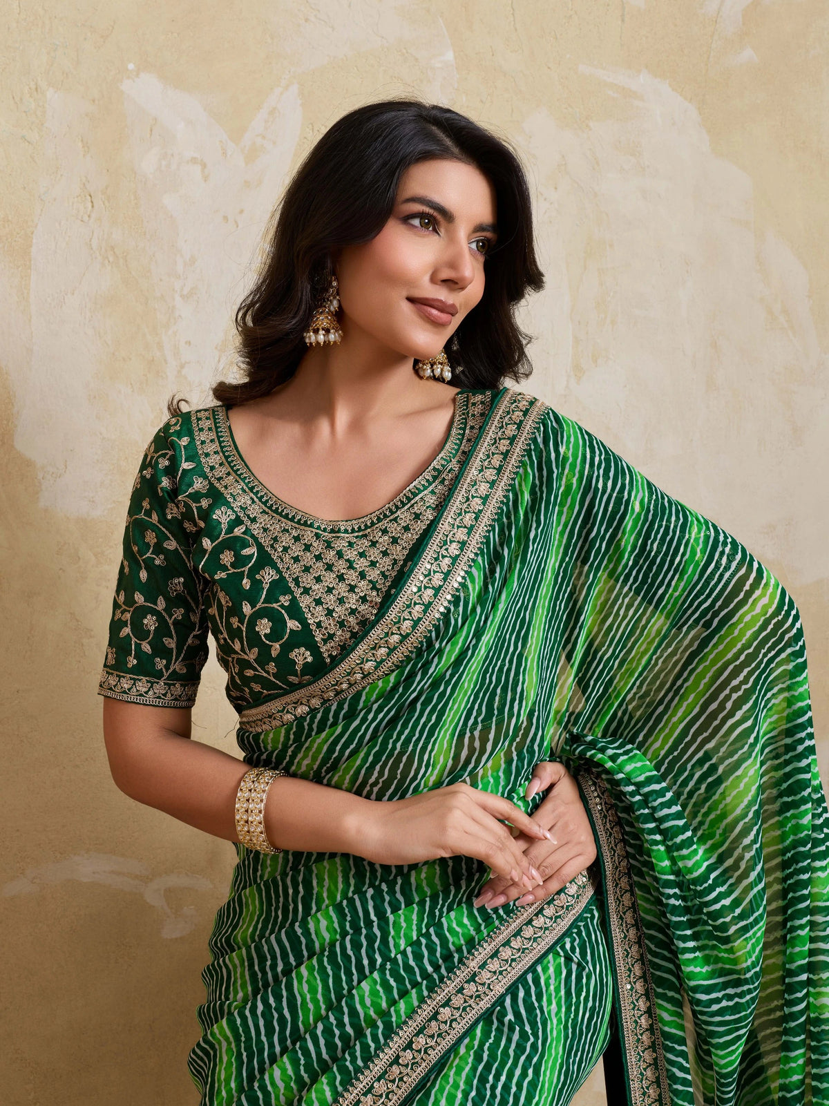 Woman wearing a green saree with a textured background