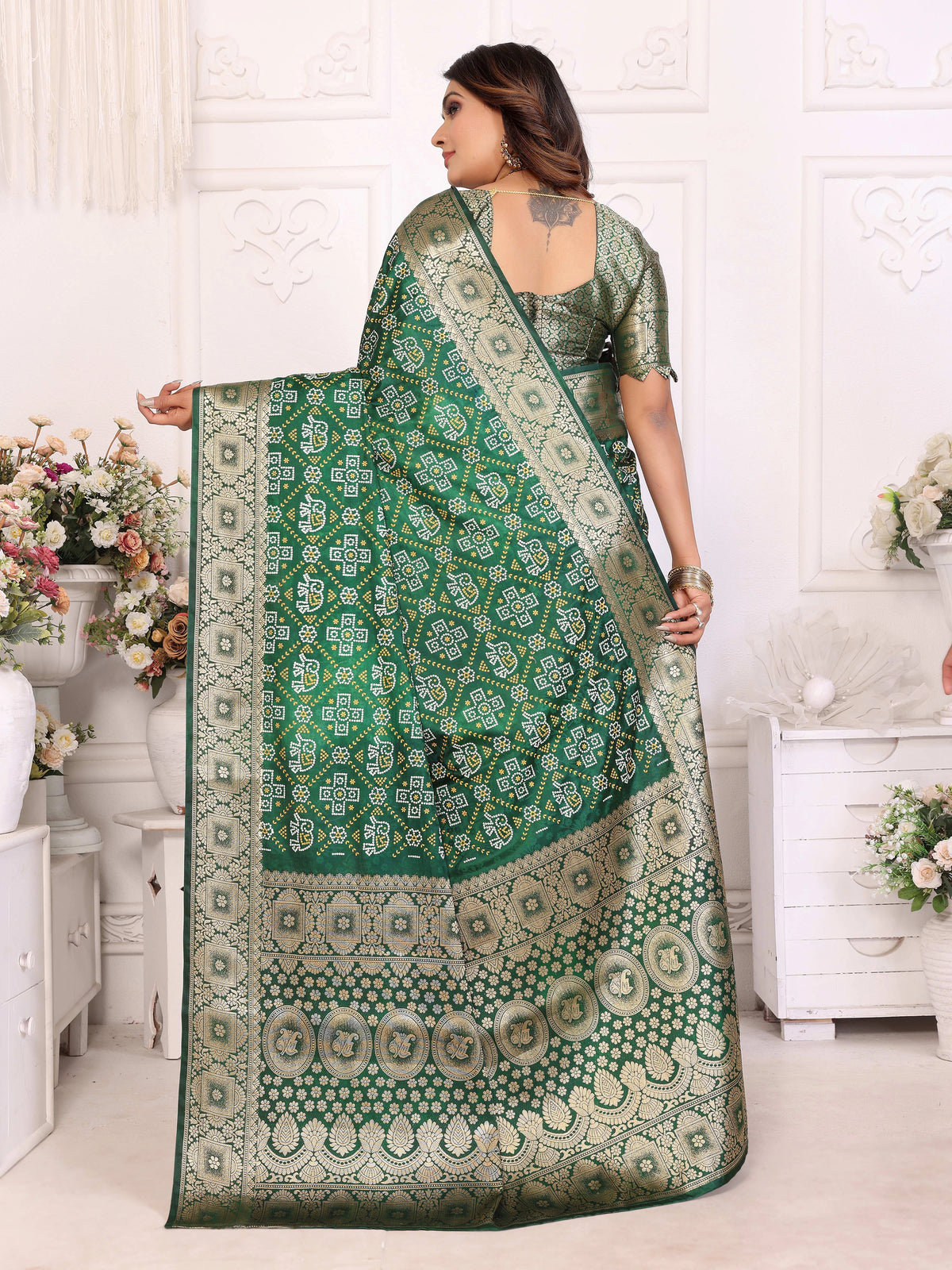 Woman holding a green and white patterned saree in a decorated room.