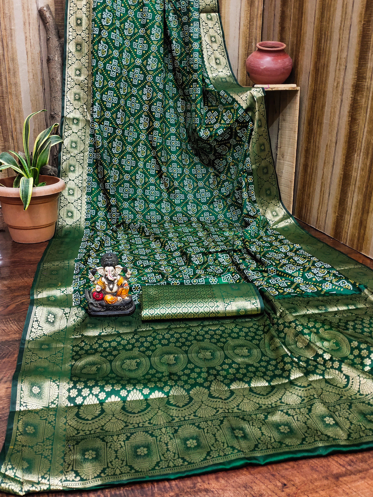 Green patterned fabric draped over a chair with a small statue and plant in the background.