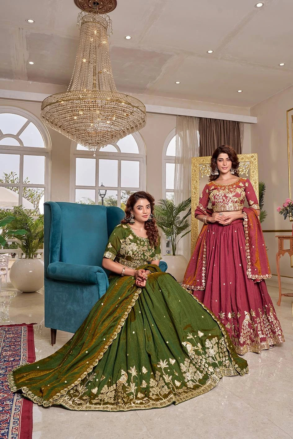 Two women in traditional outfits in a well-decorated room with a chandelier.