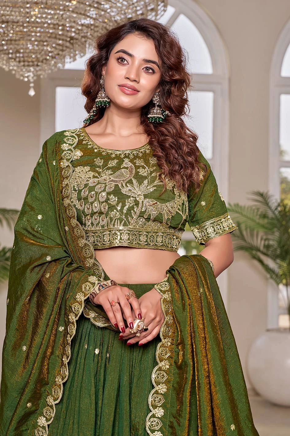 Woman wearing a green embroidered traditional outfit with a chandelier in the background