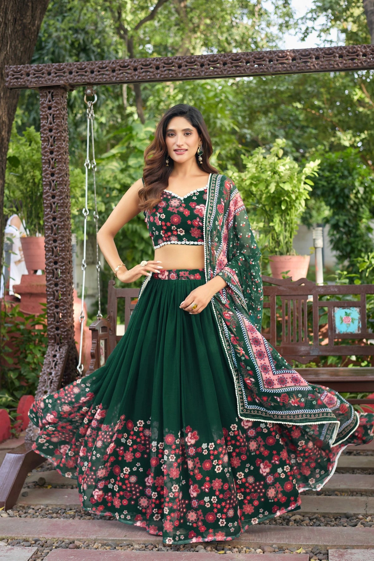 Woman in a green and pink floral traditional outfit standing outdoors.