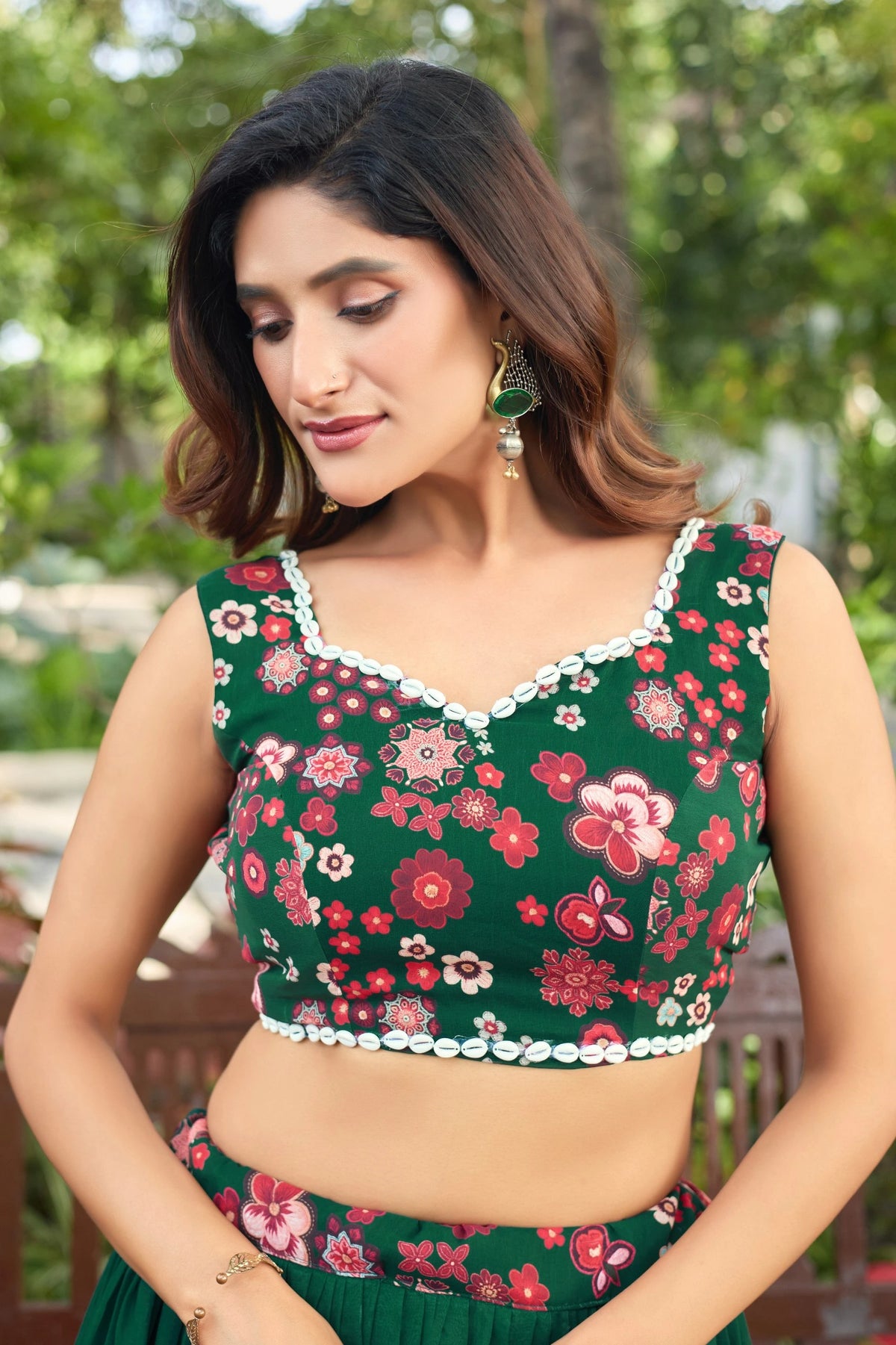 Woman wearing a green floral top with a blurred natural background