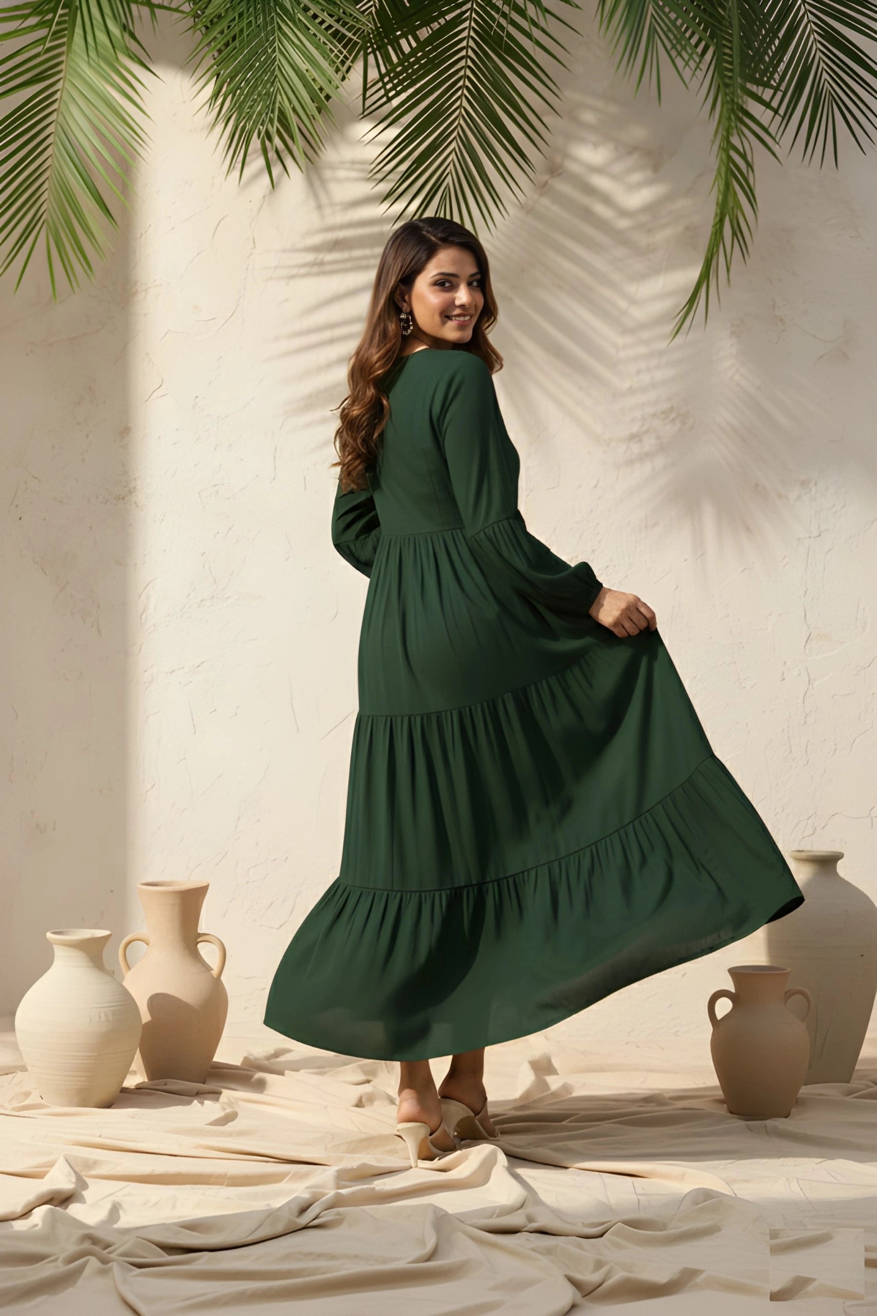 Woman in a green dress standing in a sunlit room with vases and plants.