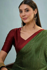 Woman wearing a green saree with a red blouse against a light blue background