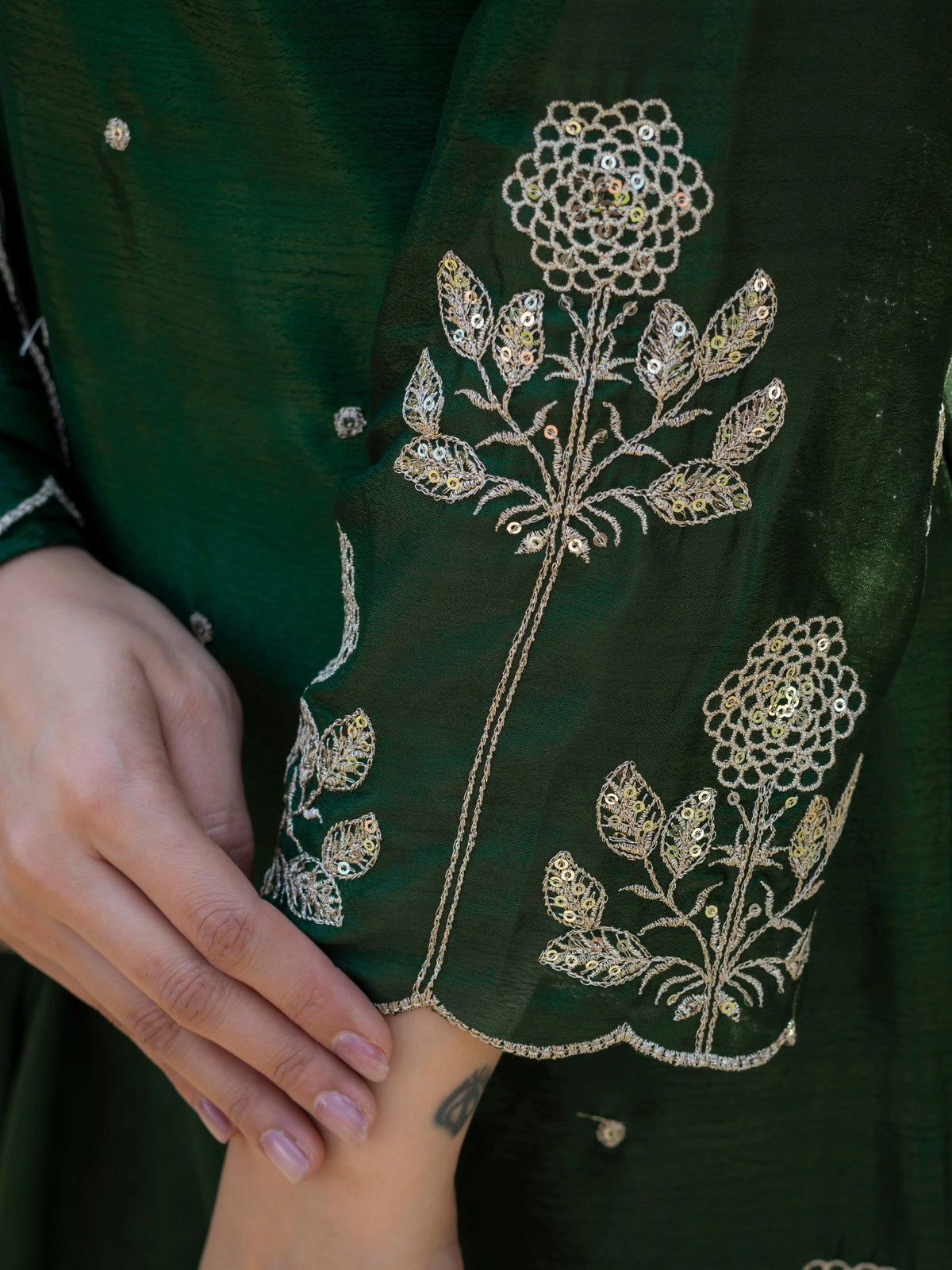 Close-up of a green garment with intricate floral embroidery and embellishments.