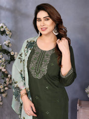 Woman wearing a green embroidered dress with a light green dupatta against a gray background with floral decorations.