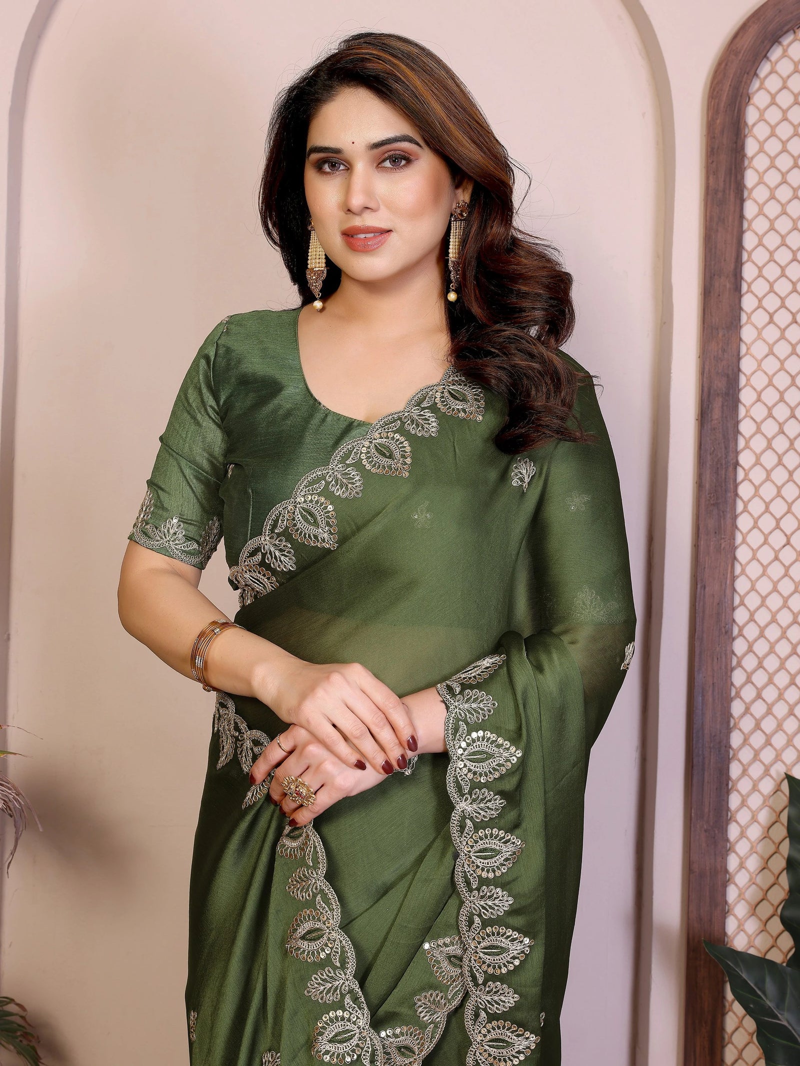 Woman wearing a green saree with silver embroidery against a neutral background