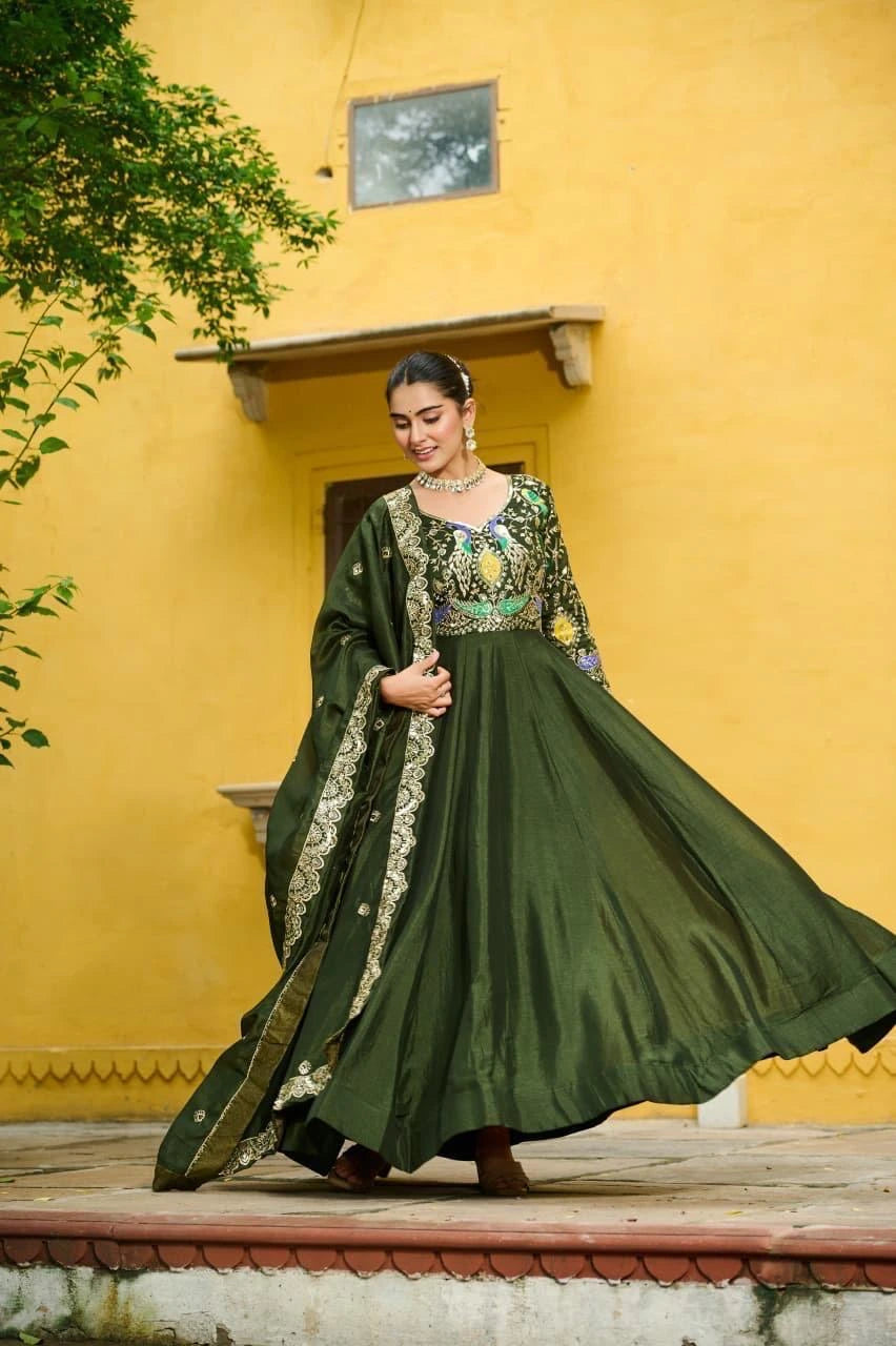 Woman in a green traditional outfit standing against a yellow wall.