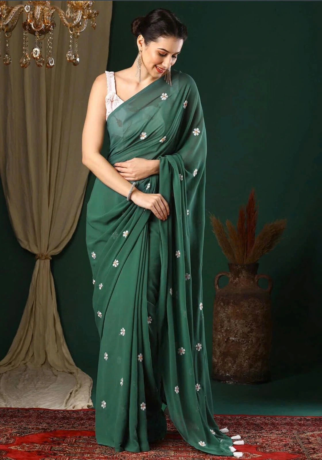 Woman wearing a green saree with silver patterns against a dark background