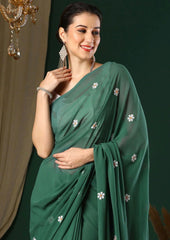 Woman wearing a green saree with white floral patterns against a dark background