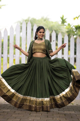 Woman in a green traditional outfit with a white picket fence and greenery in the background