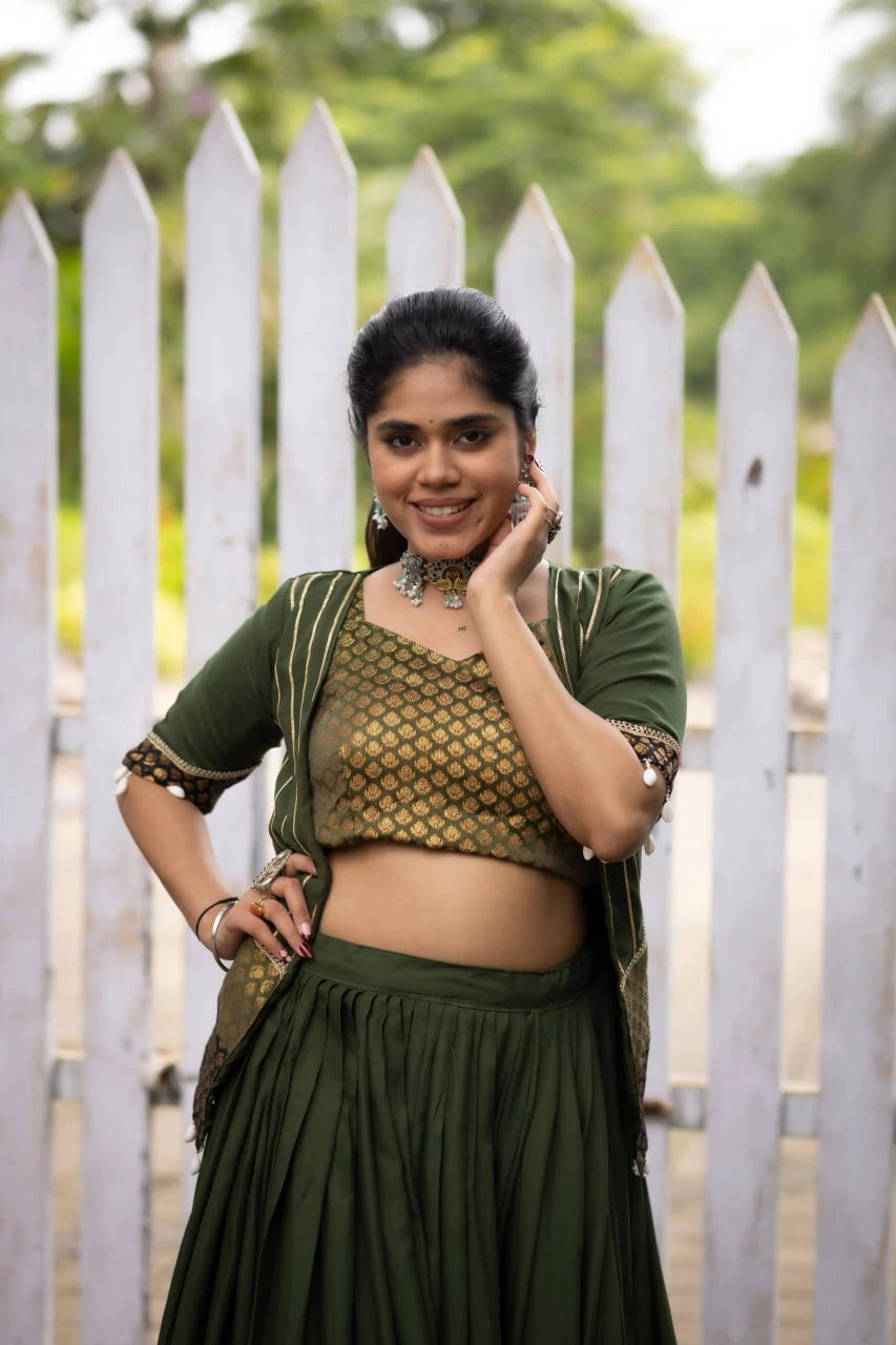 Woman in green traditional outfit standing in front of a white picket fence