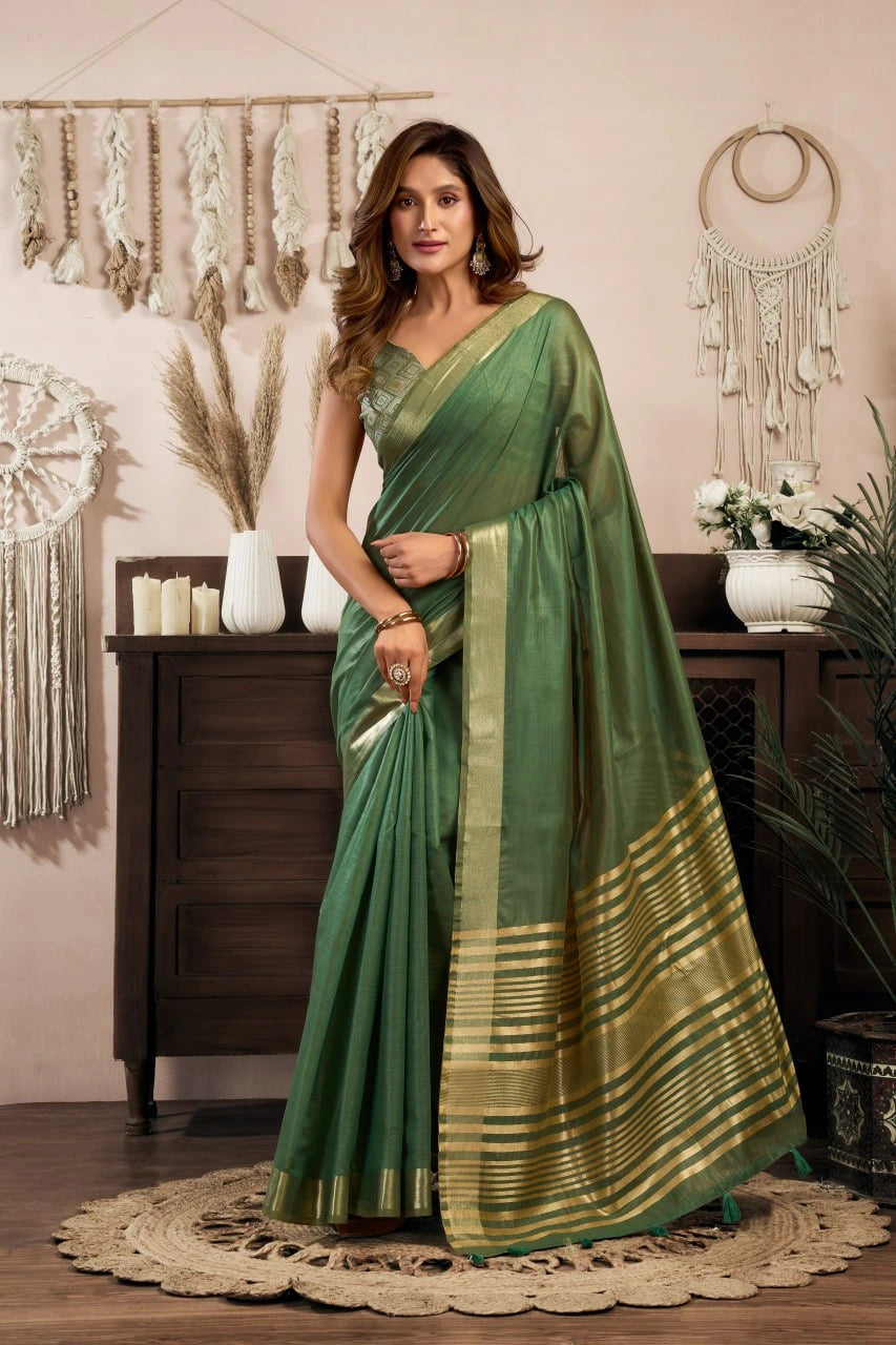 Woman in a green saree standing in a decorated room with plants and decor.