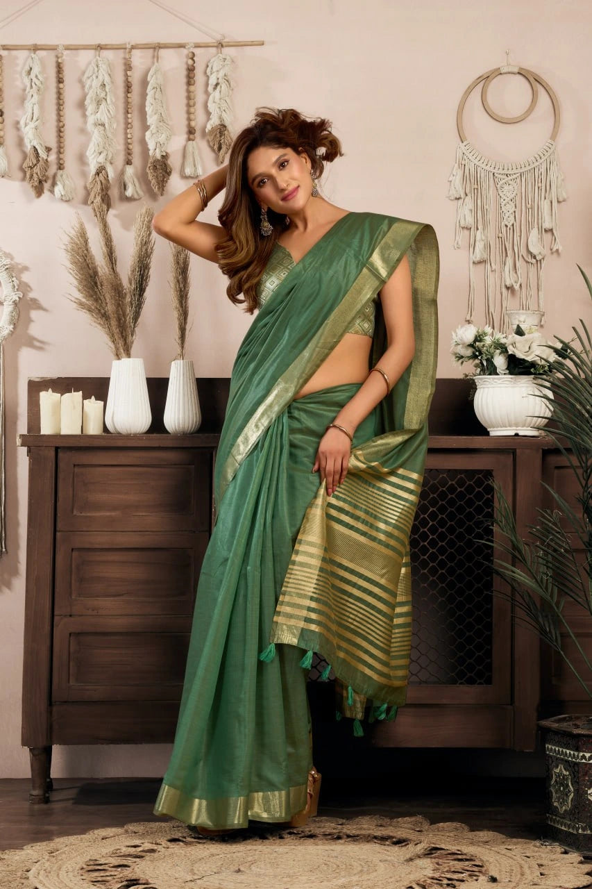 Woman in a green saree standing in a room with decorative elements.