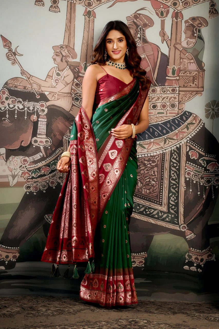 Woman in a green and red saree standing in front of an elephant mural.