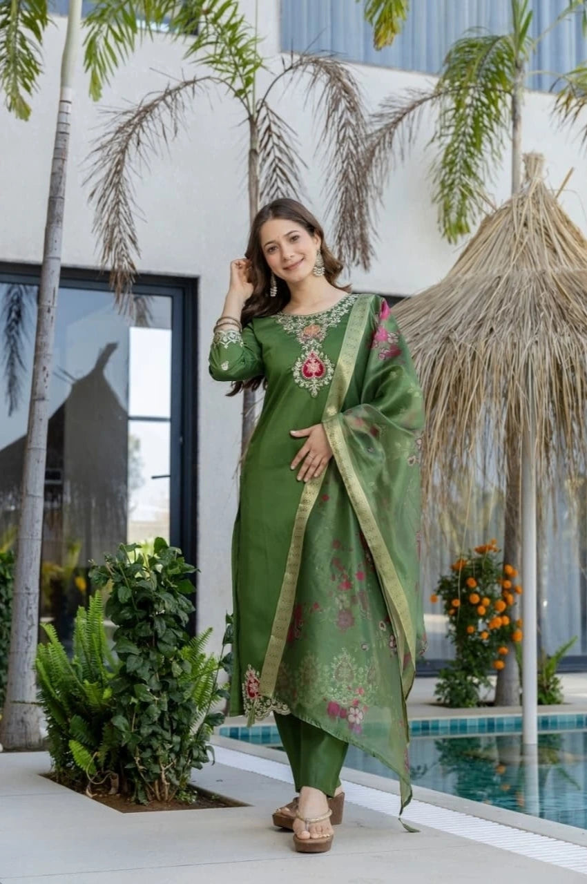 Woman in a green traditional outfit standing by a pool with palm trees in the background