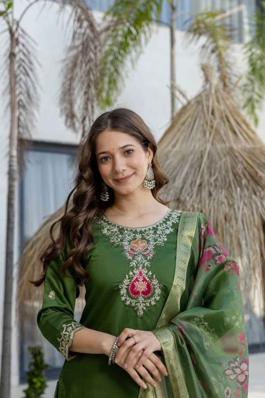 Woman wearing a green embroidered traditional outfit with a blurred outdoor background