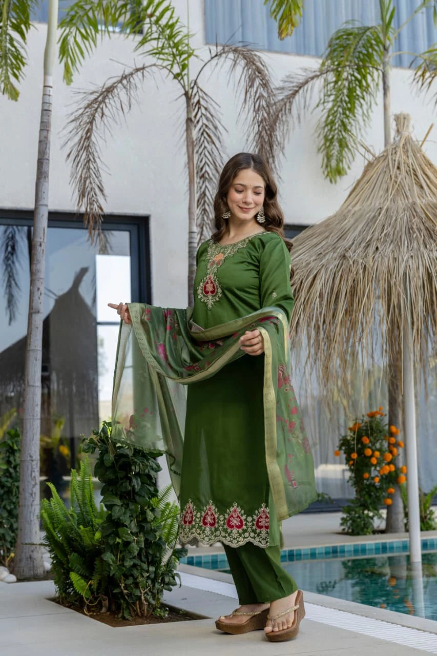 Woman in a green traditional outfit standing by a pool with palm trees in the background