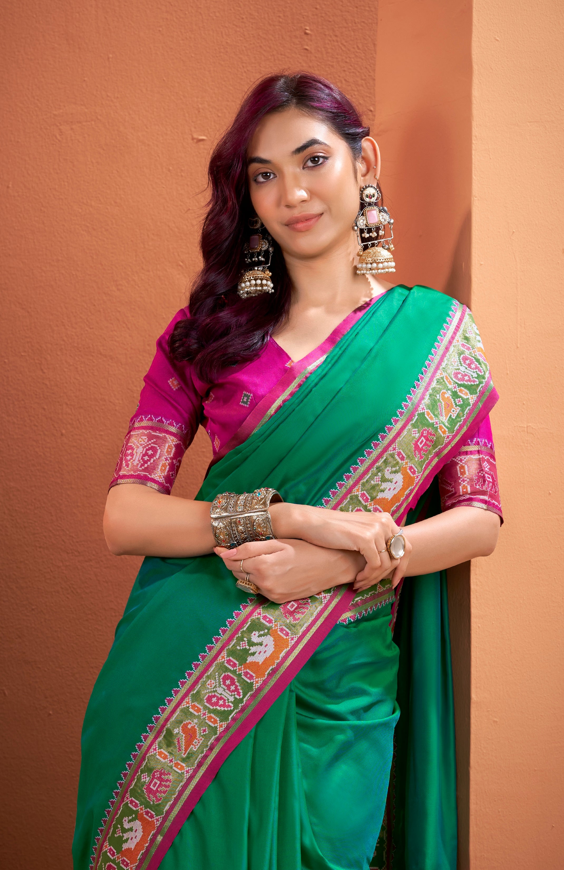 Woman wearing a green and pink saree with a brown background