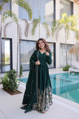 Woman in a green dress standing by a pool with a modern building in the background