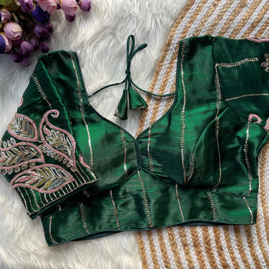 Green embroidered blouse on a textured surface with flowers in the background