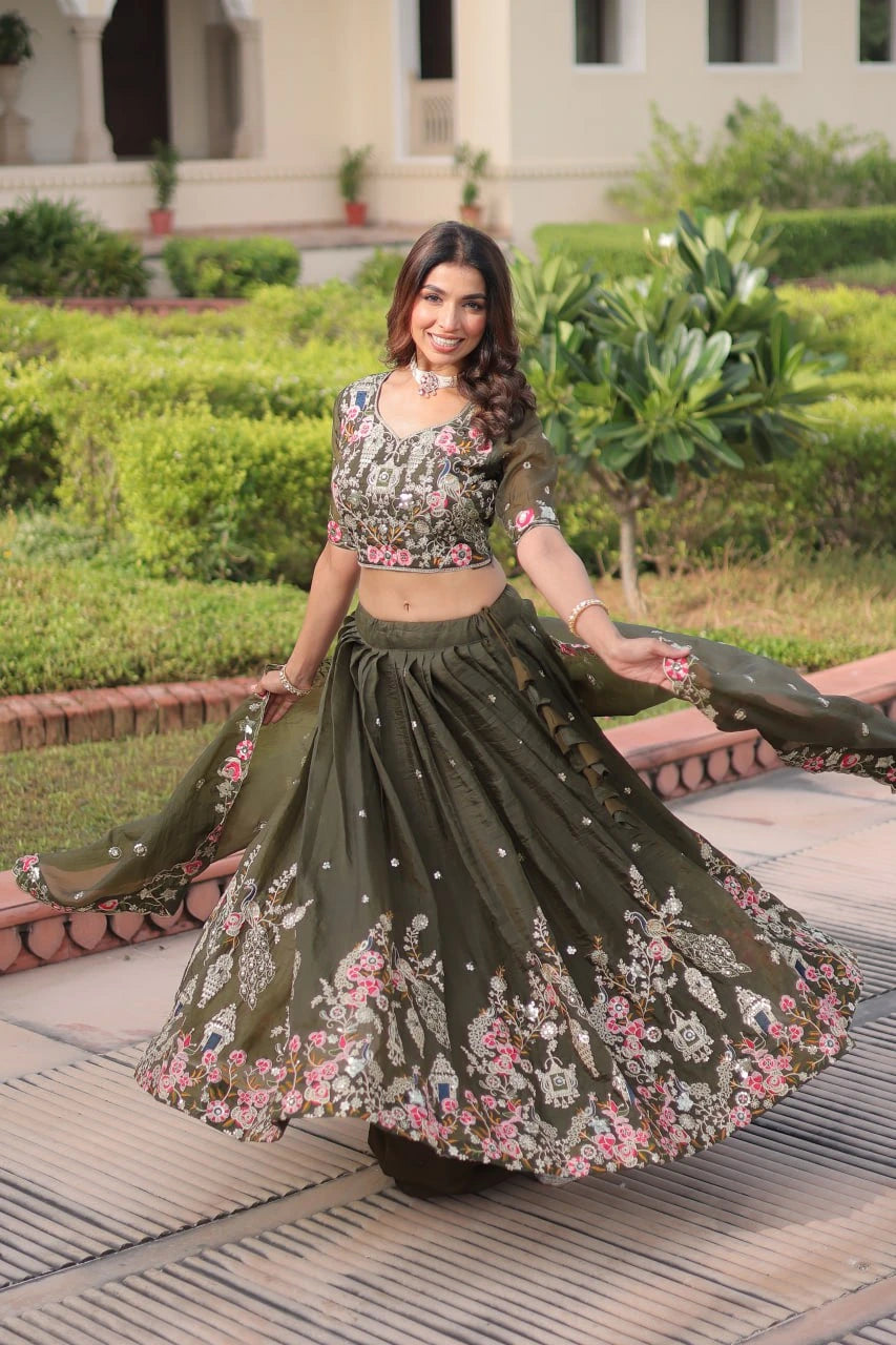 Woman in a green and floral outfit standing outdoors with greenery in the background