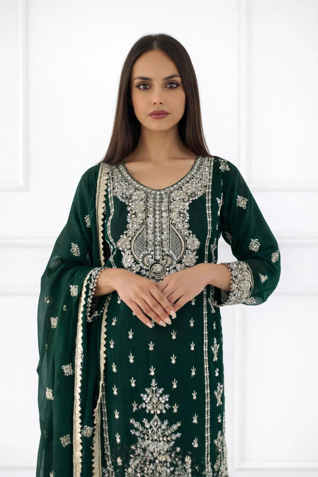 Woman wearing a green embroidered traditional outfit with a white background