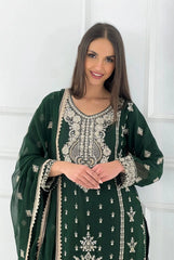 Woman wearing a green embroidered traditional outfit against a white wall