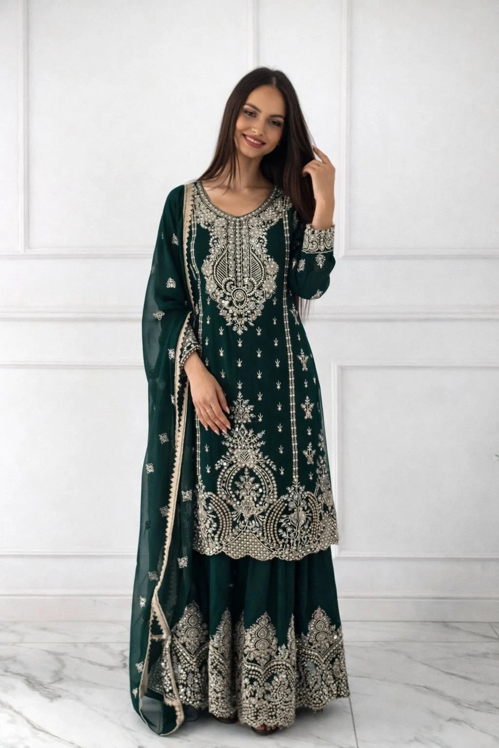 Woman wearing a dark green embroidered traditional outfit against a white background