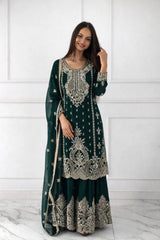 Woman wearing a dark green embroidered traditional outfit against a white background
