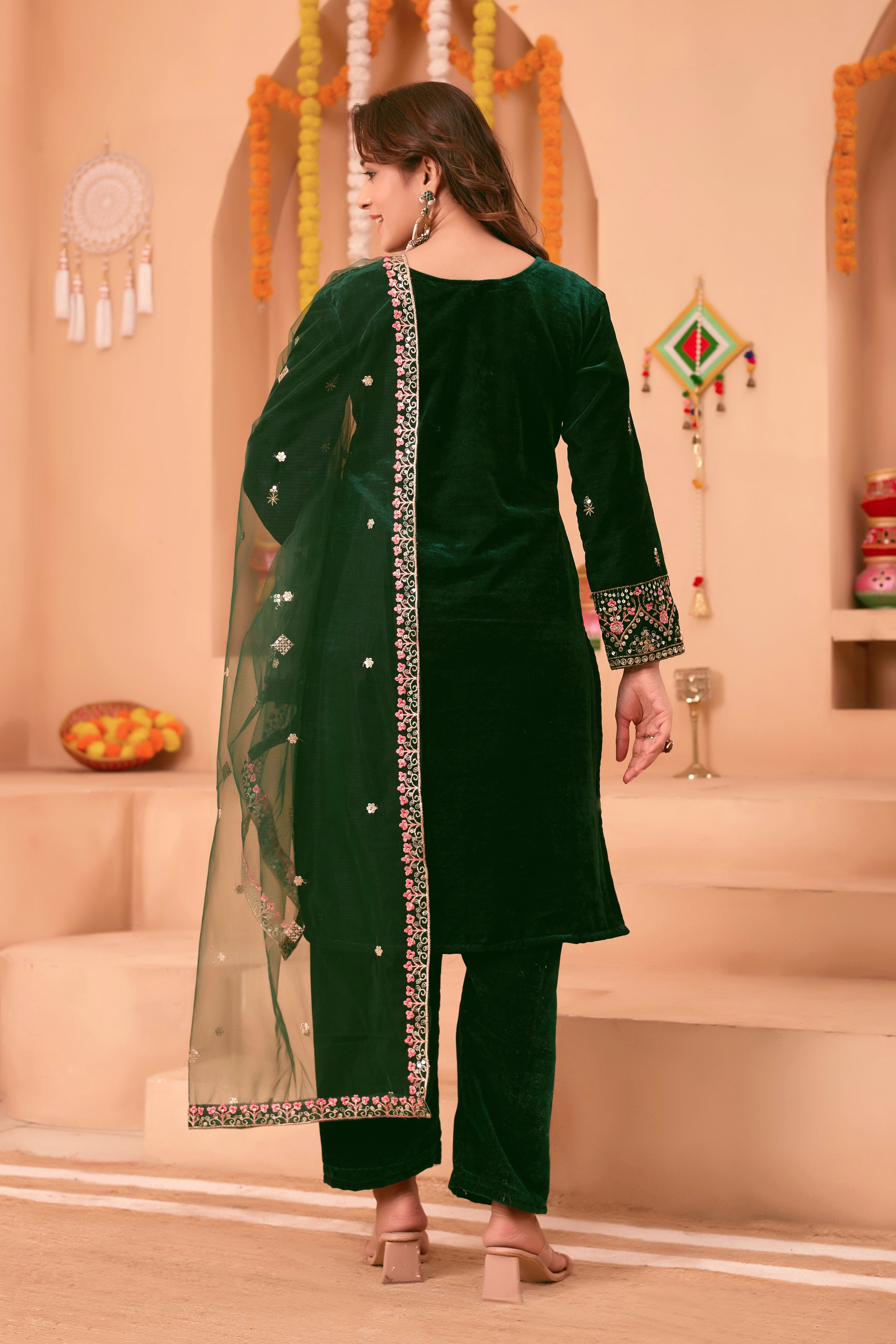 Woman wearing a green traditional outfit with a dupatta in a decorated indoor setting