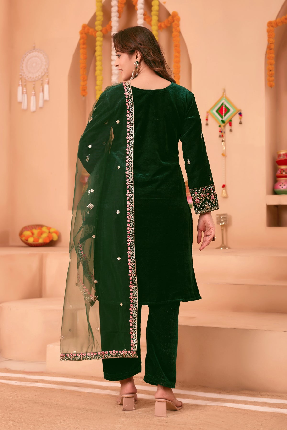 Woman wearing a green traditional outfit with a dupatta in a decorated indoor setting