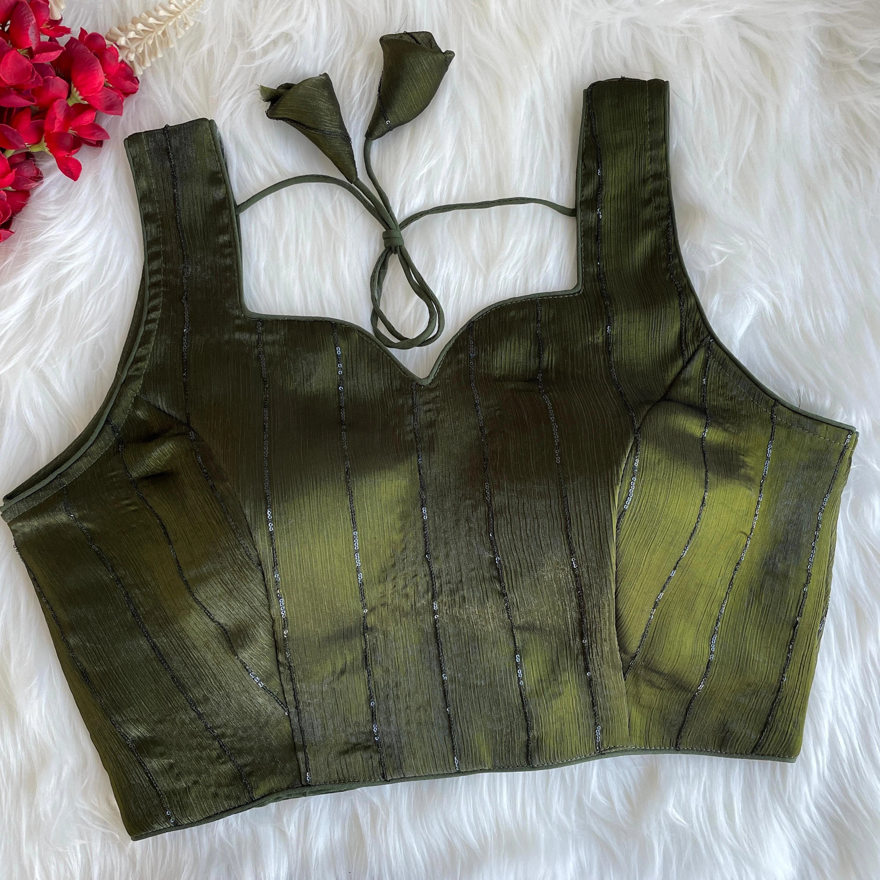 Green crop top with thin straps on a white fluffy surface with red flowers.